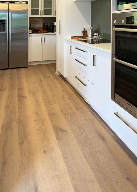 CorkWood plank flooring with a white kitchen.