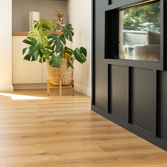 A light beige laminate floor in a kitchen, dining room and living area. Living area has a bright yellow couch.