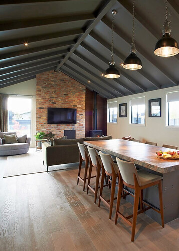 A dark wood floor in a kitchen and dining area with a dark coloured raked ceiling.