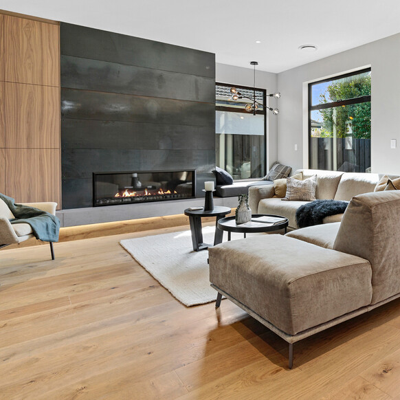 A black fireplace and open plan living area with natural wood flooring.