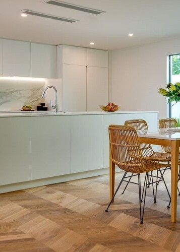 Chevron oak flooring and a pale green kitchen creates a neutral interior design style. 