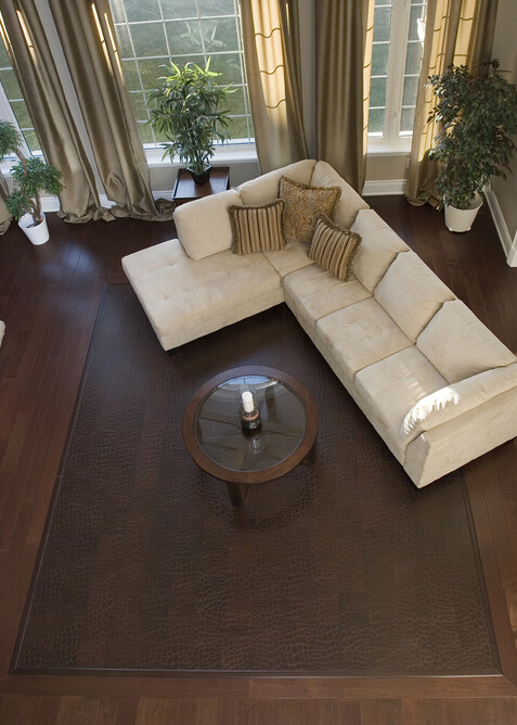 A framed brown leather floor in a living area with a cream couch and big windows.