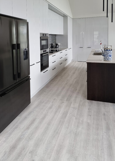 A grey laminate floor in a black and white kitchen.