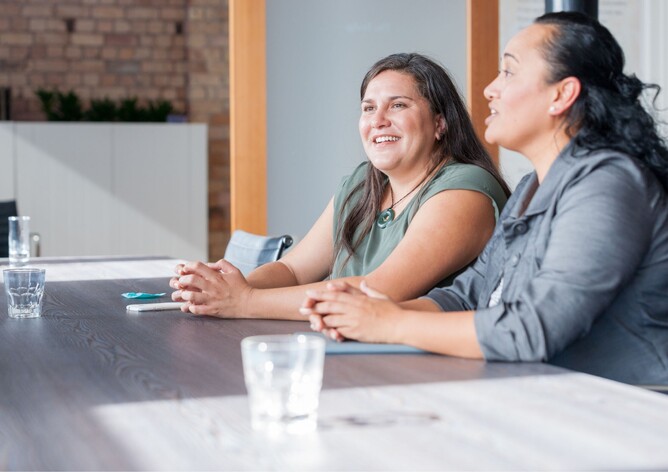 Two maori ladies sitting in a board room talking