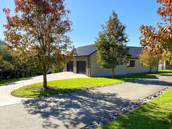 A view of the barn from the driveway lined with trees 