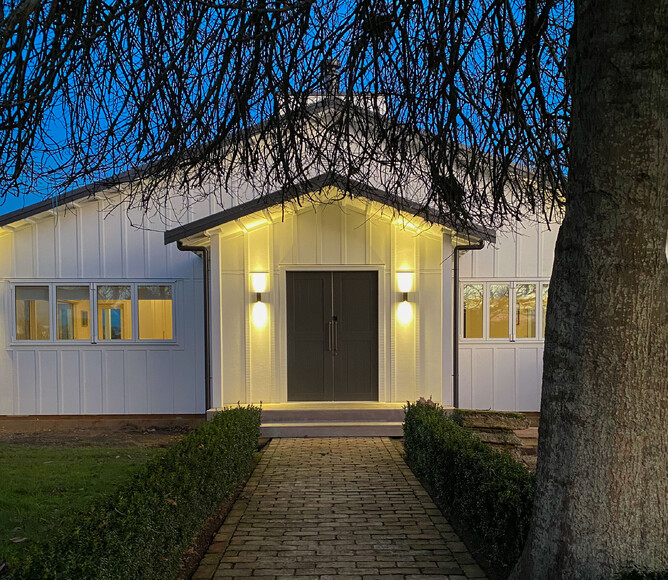 Country home entry at night with lit landing