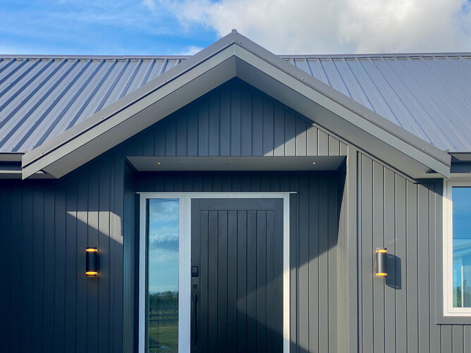 Gable entrance of country home with black cladding and roof