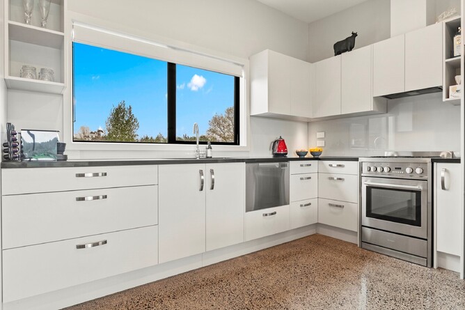 Minor dwelling kitchen area with white cabinertry and polished concrete floor