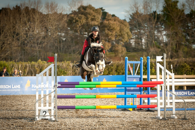Mya Thomas and her horse Cabbana jumping a fence in the arena