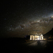 SkyScape cabin illuminated beneath a clear night sky