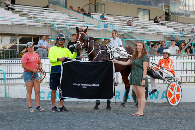 Sacred Mountain in the winner's circle with, from left, stable helpers Leah Hibell and Gary Gillies, and Cambridge Raceway's Ashleigh Hopping. - Photo: Angelique Bridson