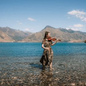 Erica standing in Lake Whakatipu Queenstown, playing her violin.