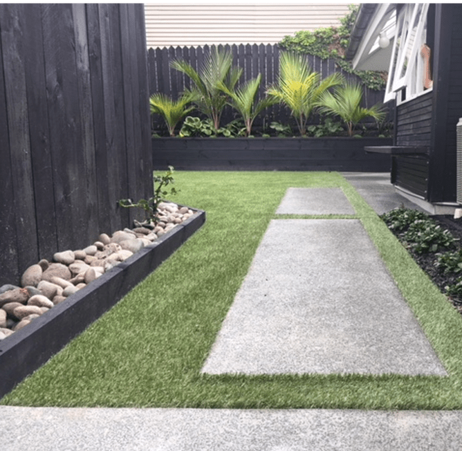 Low cost landscape ideas for NZ Garden with subtropical plants, black painted fences and walls, stone mulch and artificial turf