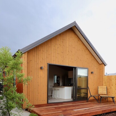 A front, side view of the home extension. The home is clad in Luna timber cladding with dark colour steel roof, and a timber deck in front.