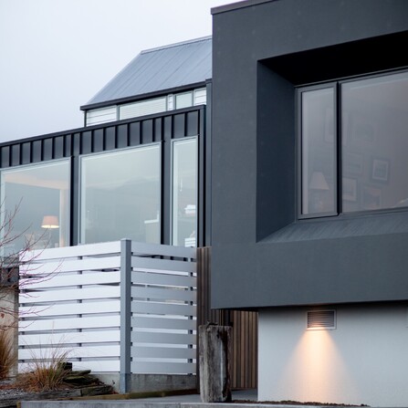 The exterior of the home with feature lighting and large windows looking out.