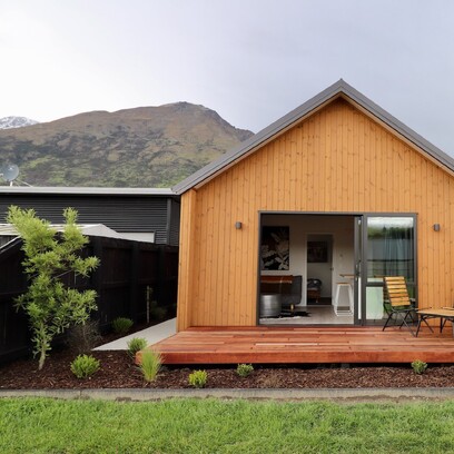 The front of the house extension clad in Luna Wood, with a sliding door opening onto timber decking.