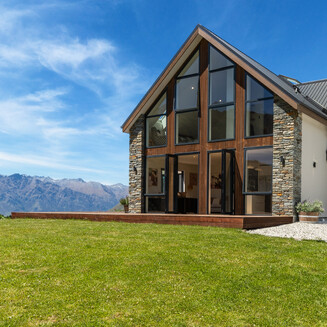The front of the house extension clad in Luna Wood, with a sliding door opening onto timber decking.