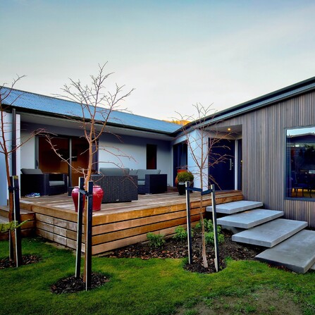 A spacious outdoor entertaining area with a large timber deck and stacked concrete steps leading onto it.