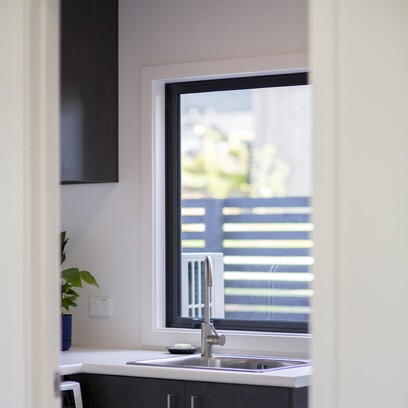 A stylish yet practical laundry area with white walls and dark cabinetry.