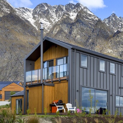 Looking up at the end of the house with the balcony and the Remarkable Mountain range in the background.