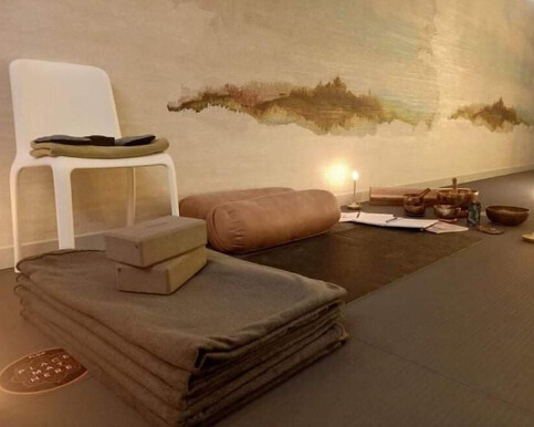 a photo of a yoga class set-up in the Earth Studio, featuring a yoga mat. blanket, bolsters, and blocks