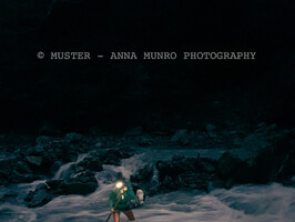 Shepherd female crossing cold river with headtorch. Merino muster with dog. Autumn Muster.  Lake Heron Station, Canterbury High Country, New Zealand