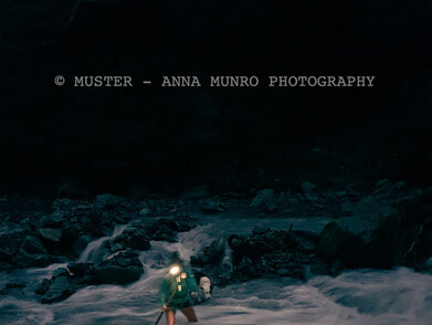 Shepherd female crossing cold river with headtorch. Merino muster with dog. Autumn Muster.  Lake Heron Station, Canterbury High Country, New Zealand