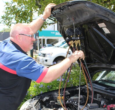 Technician checking pressure gages on a refrigerant machine during a de-gas