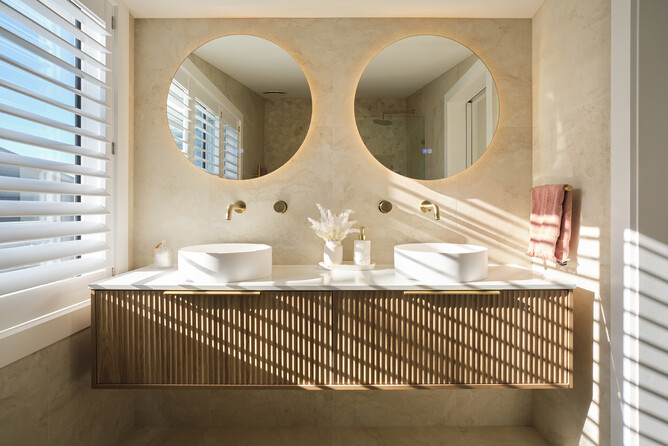 A modern bathroom renovation with double vanity and twin round mirrors. 
