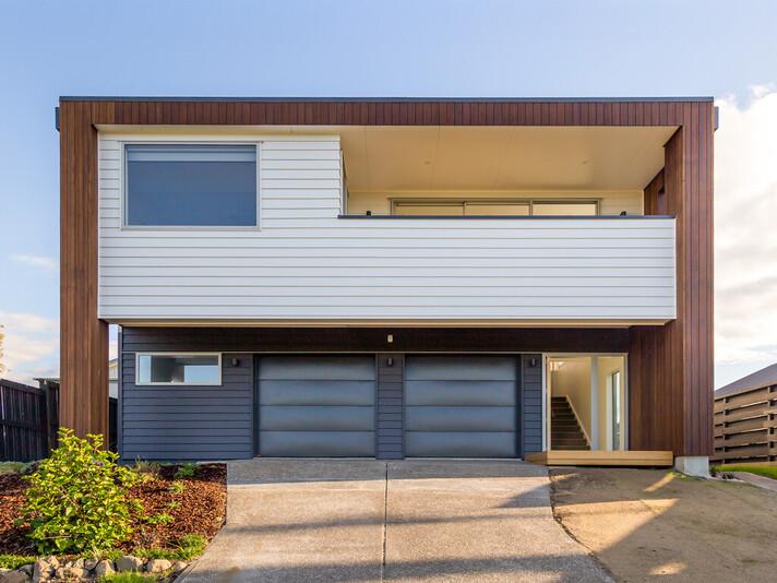 The image shows a newly renovated home with modern road frontage. Renovation build completed by Straight Up Builders Tauranga
