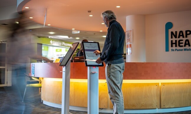 Patients being checked-in with NZ Code kiosks