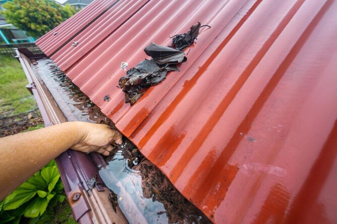 A view of spouting blocked with leaves and water on top of a home.