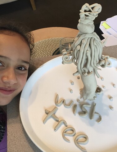 Young girl smiling beside her clay wish tree