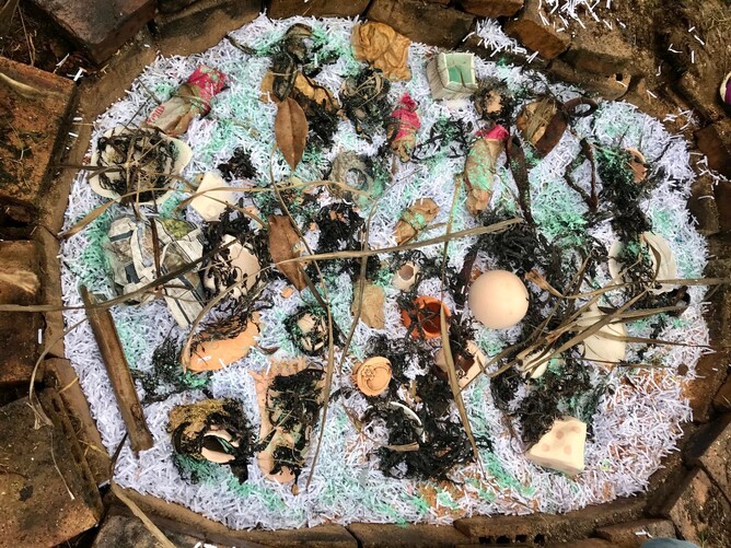 ceramics nestled in shredded paper, with cabbage leaves and seaweed around them, sprinkled with green powder