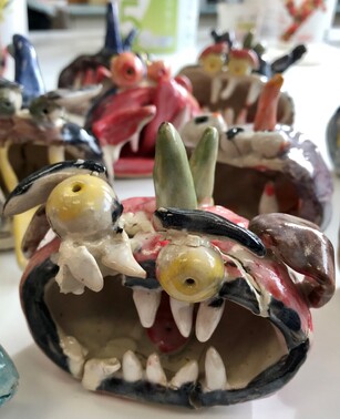 A cluster of multicoloured ceramic monster faces made by children