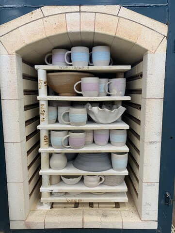 An open kiln loaded with unfired glazed ceramics