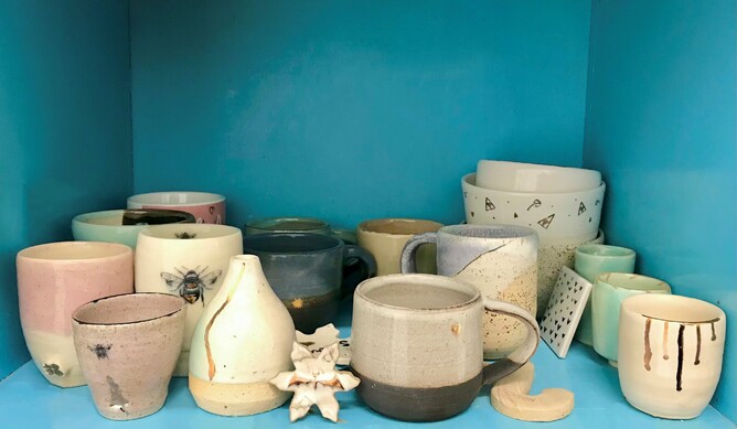multiple pieces of ceramics decorated with metallic overglaze, sitting on a bright blue shelf