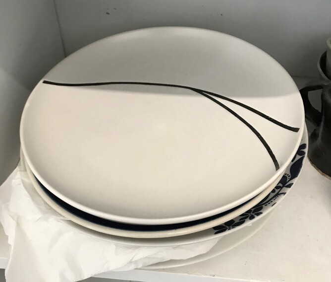 A stack of white plates with some black patterning