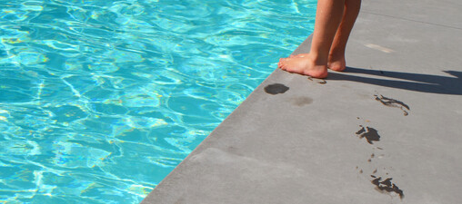 Image of cropped legs standing next to a cropped in part of a swimming pool