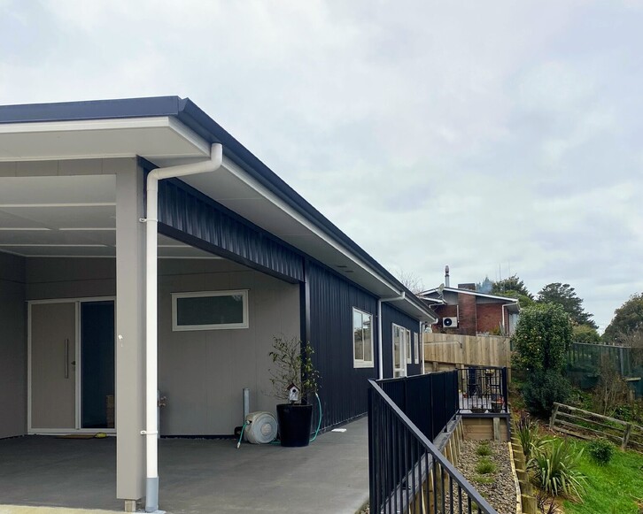 Image of fresh laid concrete at front entrance of low roof home, and new fencing.