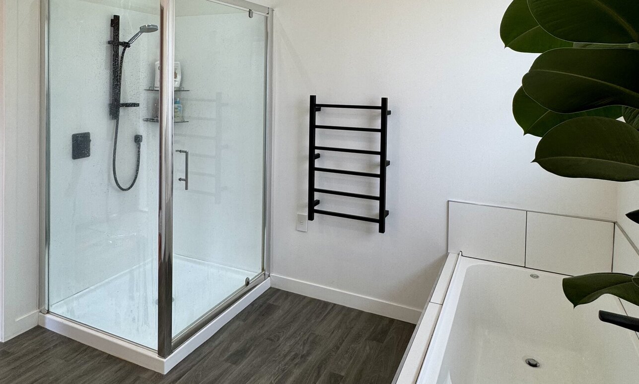 Fresh new white tiled bath, toiler and black tiled bathroom by Coull Builders, Otorohanga.