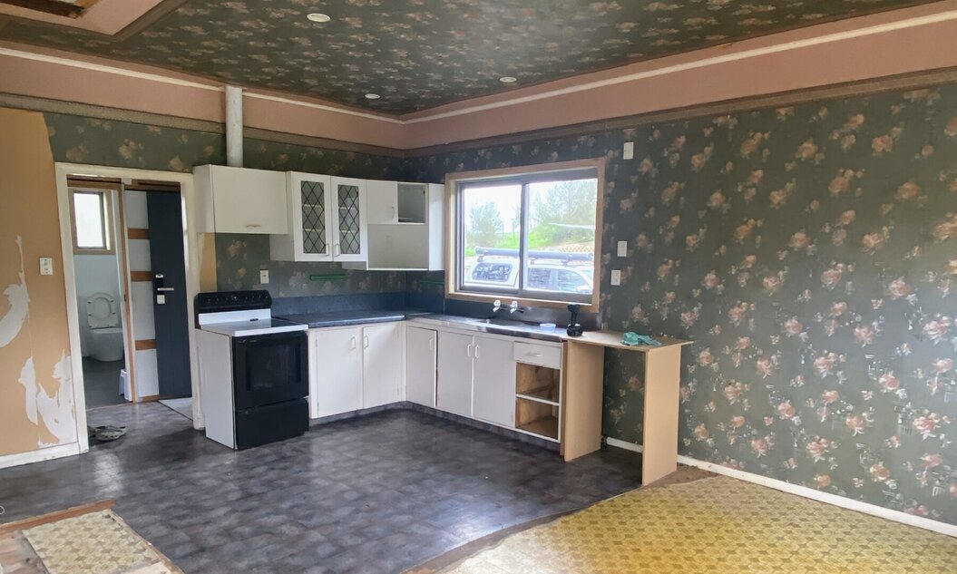 Image of dated kitchen, living space and old fashioned floral wallpapered walls & ceilings prior to its renovation by Coull Builders.