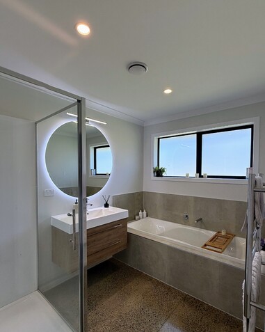 Image of modern light new bathroom with neon lit round vanity mirror. New home by Coull Builders, Otorohanga.