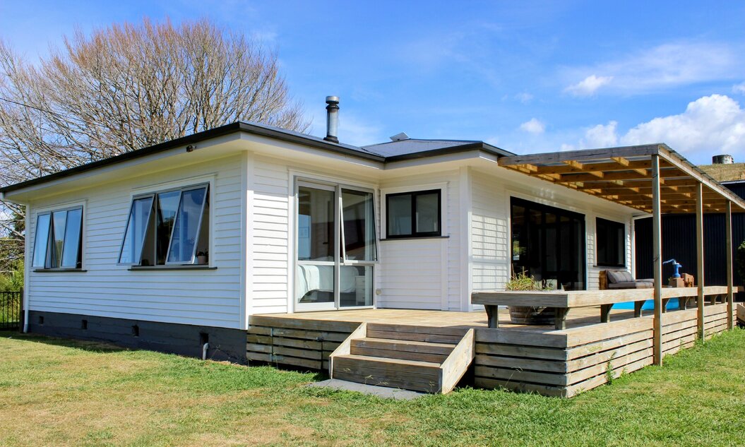 Image of the recently renovated weatherboard home painted white with dark roofing and new decking. By Coull Builders, Otorohanga.