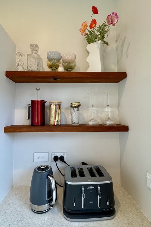 Image of rustic wooden floating shelf with decorative glasses, whiskey decanter and flowers. Renovation by Coull Builders, Otorohanga, Waikato.