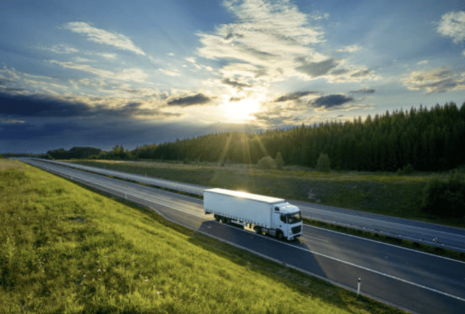 Heavy commercial truck on a motorway with the sun setting behind