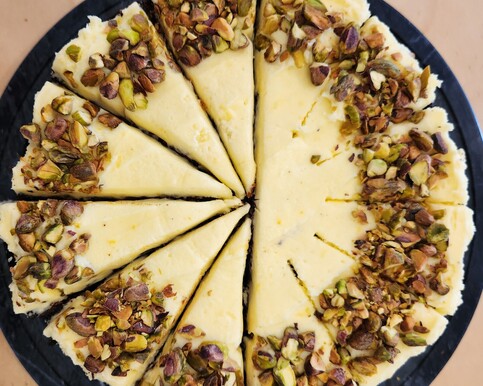 Full carrot cake topped with cream cheese icing and pistachio garnish