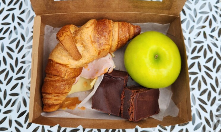 each lunch box. ham and cheese croissant, chocolate brownie and green apple.