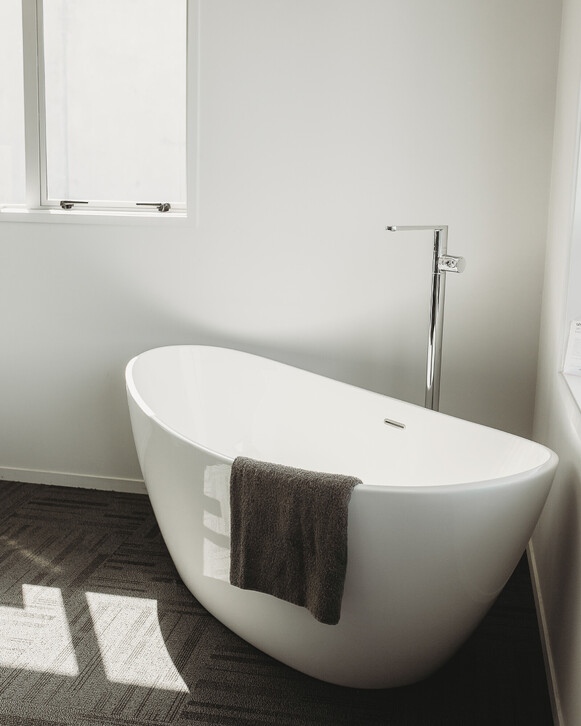 Image from Gane Plumbing's showroom. Deep white bath with chrome floor standing mixer. Te Awamutu, New Zealand.