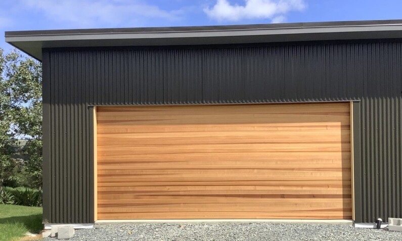 Photo of a timber garage door fitted to a home in Rodney, Auckland. Horizontal wooden board pattern